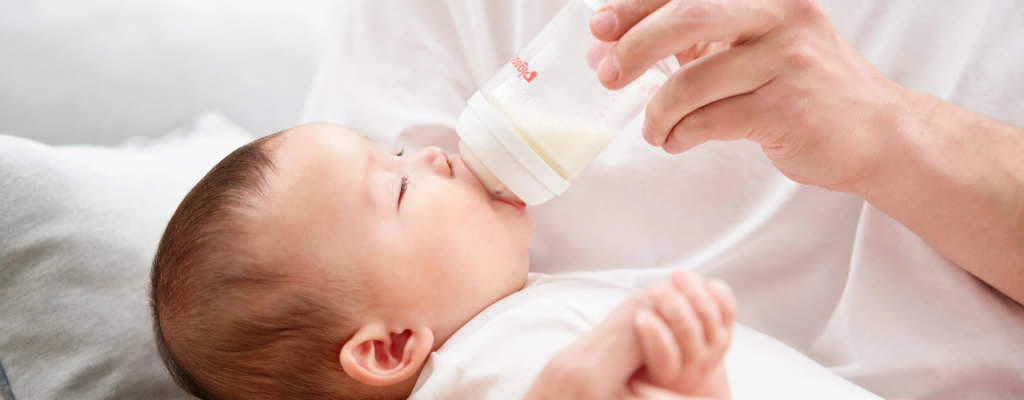 a baby being fed with pigeon softouch baby bottle