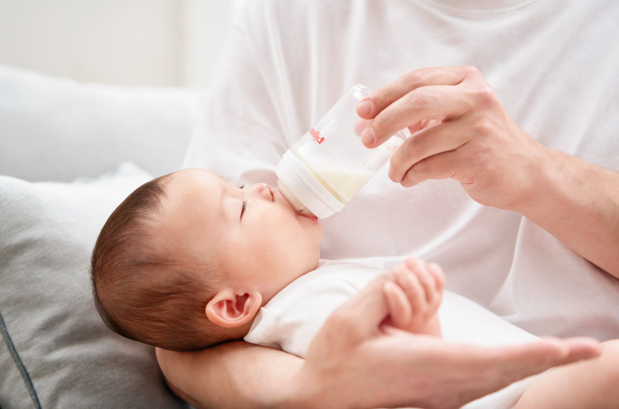 baby being fed from a pigeon baby bottle