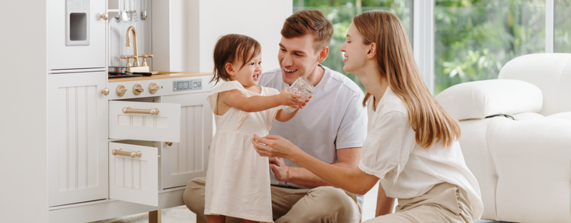 girl toddler holding cup around her parents