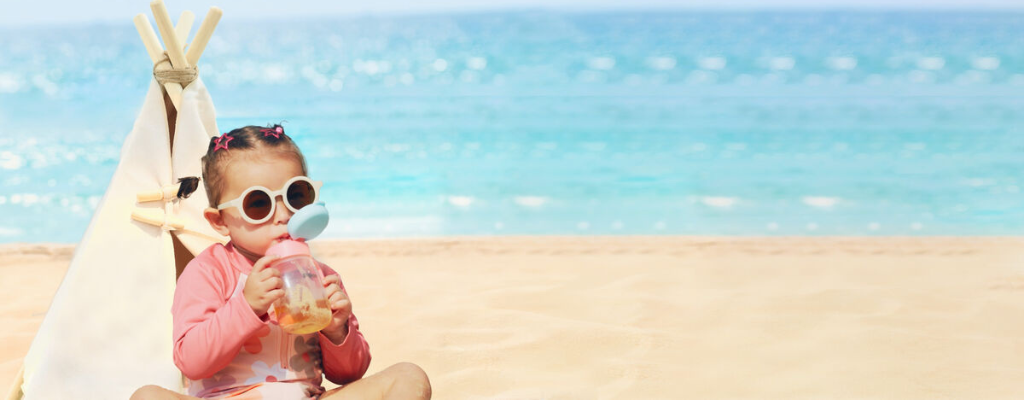 child drinking from straw cup at beach