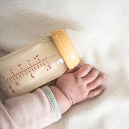 anti colic baby bottle, featuring a baby's hand